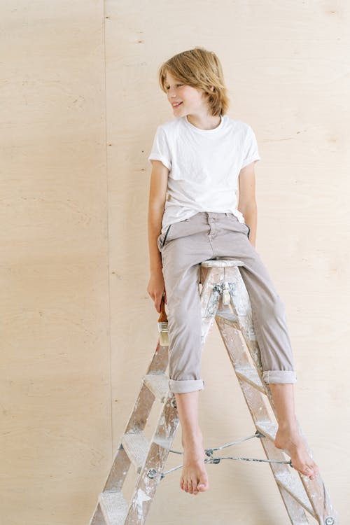 A Boy Sitting on a Ladder 