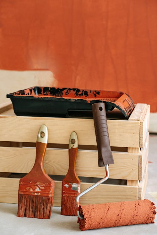 Paint Brushes and Roller Near A Wooden Crate With Tray