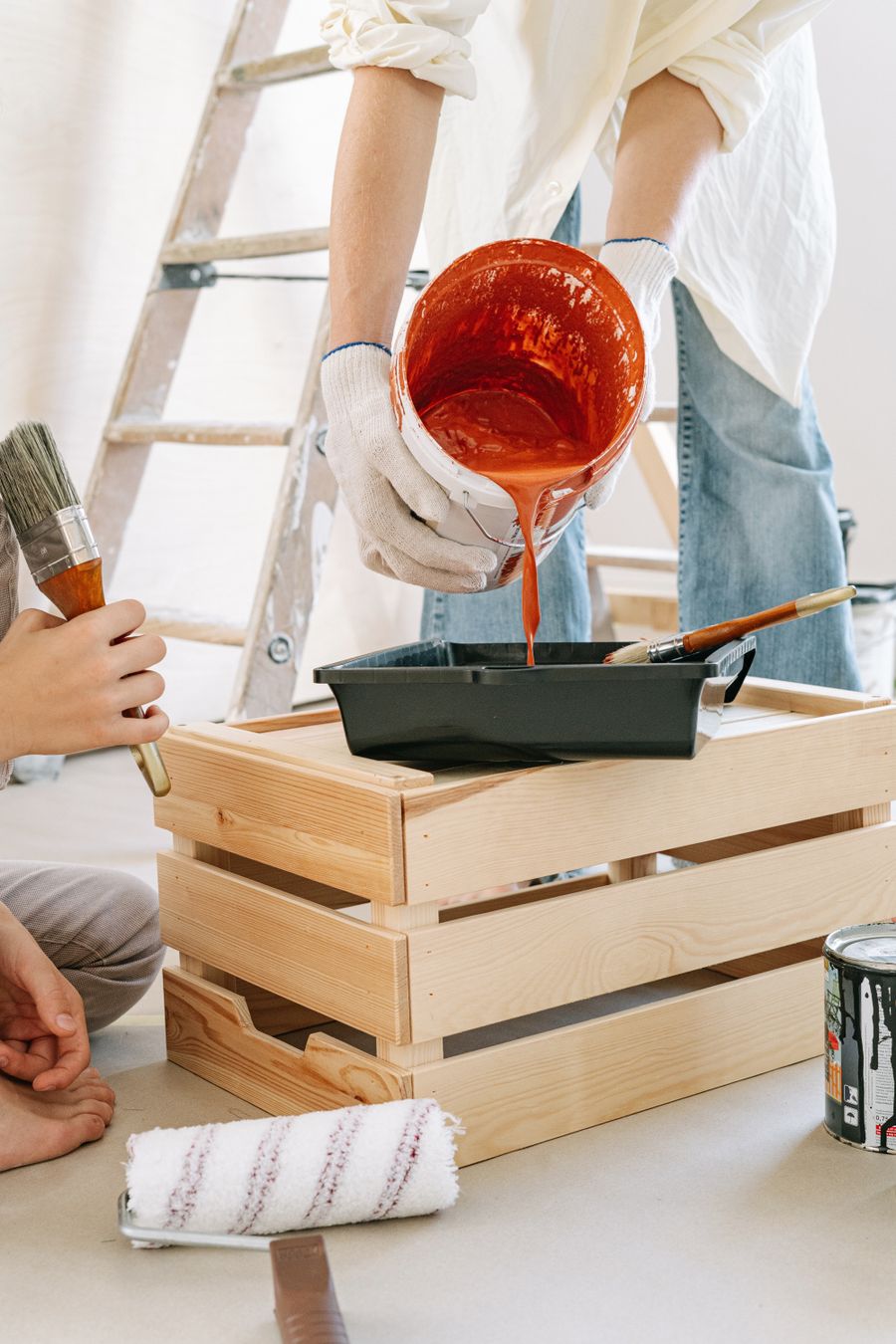 Painter pouring terracotta paint from a can into a tray