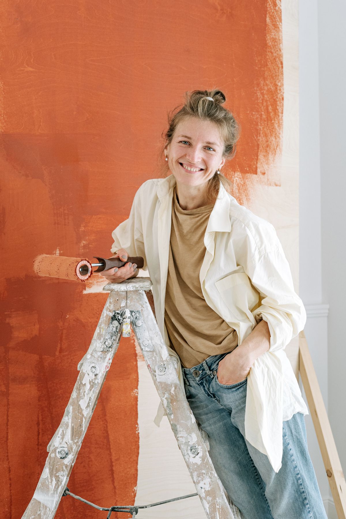 Artisane appliquant de la peinture sur un mur intérieur