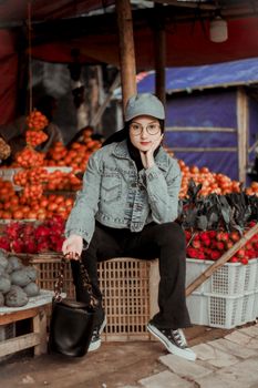 Portrait of a young woman at a lively market stall, surrounded by colorful fruits and vegetables. - Fotografer Sidoarjo
