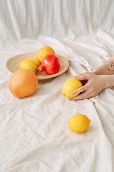 将充满活力的柑橘类水果和苹果用手排列在亚麻布上，营造出清新自然的外观