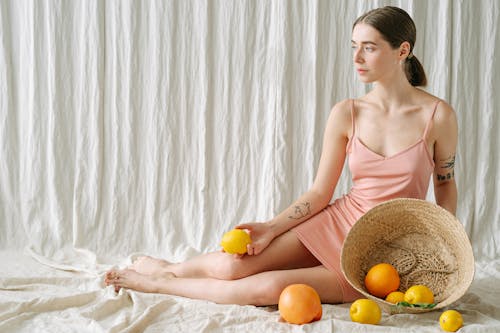 A Tattooed Woman Holding a Lemon