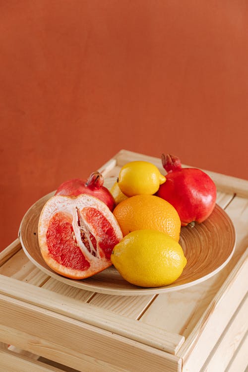 Red And Yellow Citrus Fruits on Brown Plate