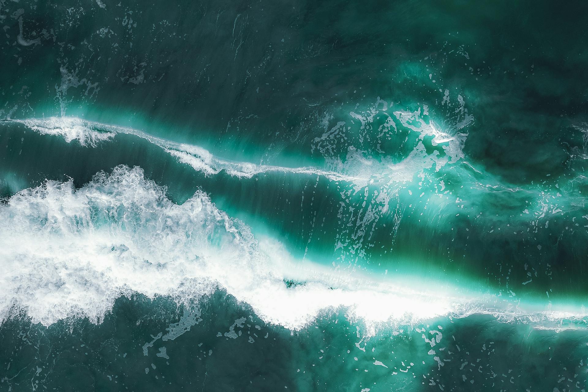 From above of turquoise water of ocean with white foam and waves in summer