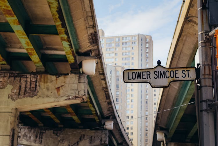 Street Sign Placed On Pole Between Old Overpasses