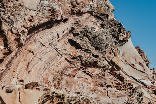 Macro of natural texture of solid light brown surface with cracks and pores on clear blue sky