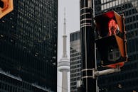 Traffic light with red color and TV tower between skyscrapers