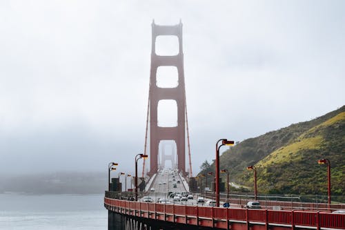 Free Golden Gate Bridge with cars driving on roadway along green hills in dense fog Stock Photo