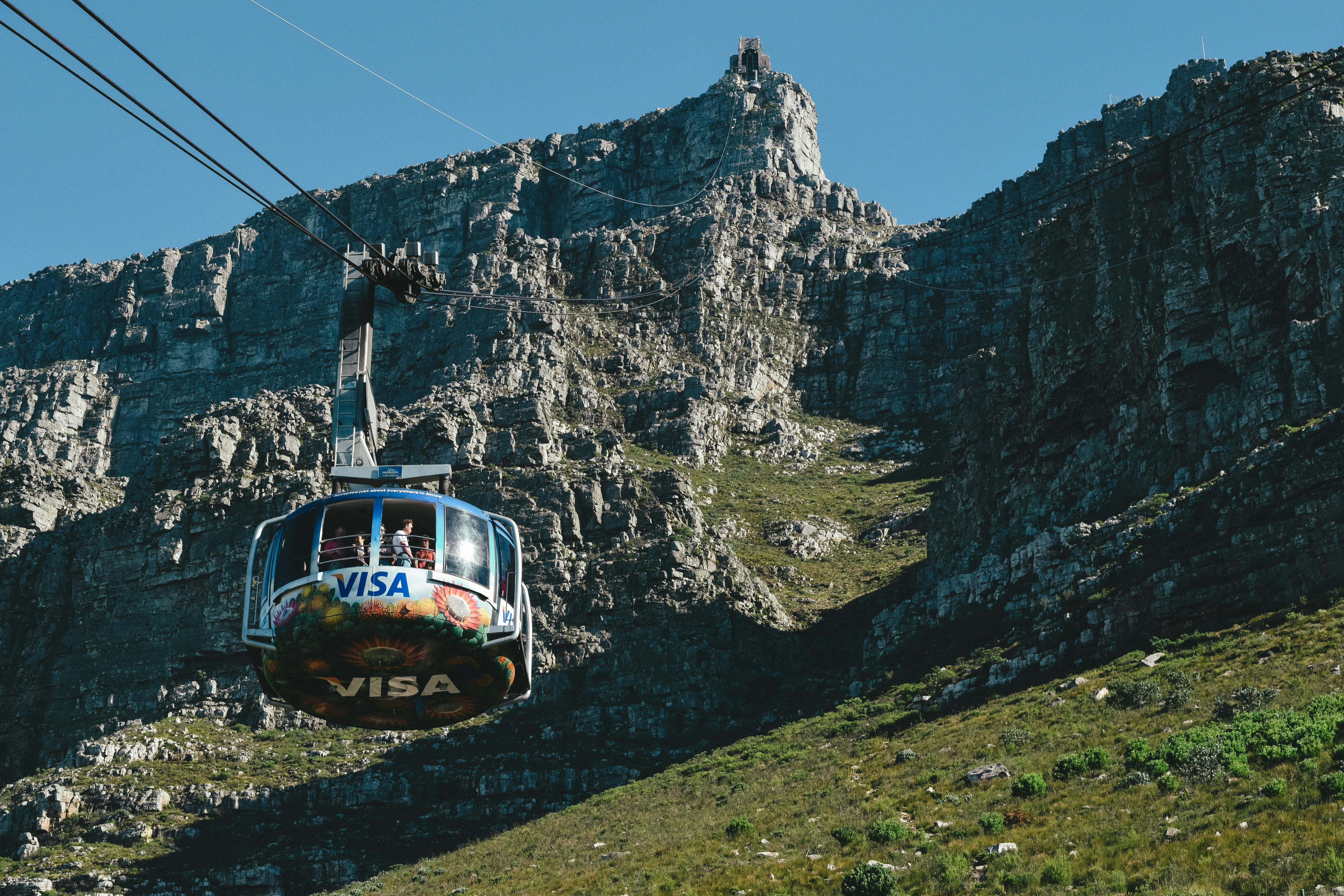 From below of colorful cabin of cableway above green meadows in cliffy mountains