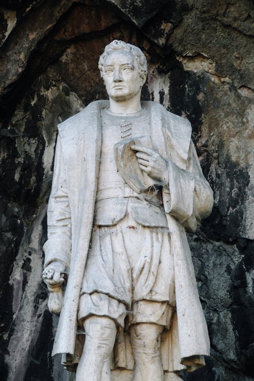 Low angle of old white marble statue of person in ancient stone cave