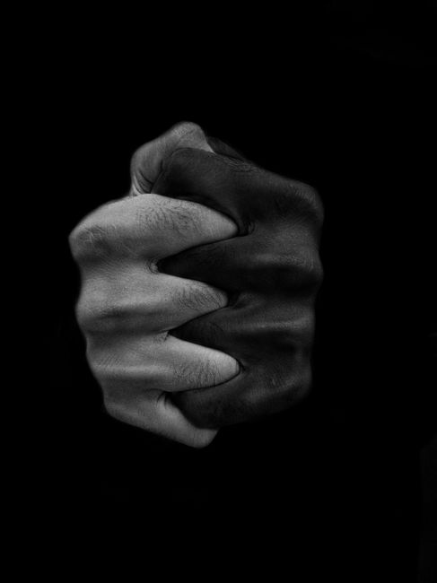 Black and white of crop hands of anonymous multiethnic people on black background