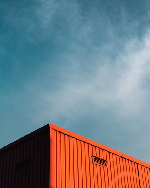 Free Low angle view of a red shipping container with a blue sky background, capturing industrial aesthetics. Stock Photo