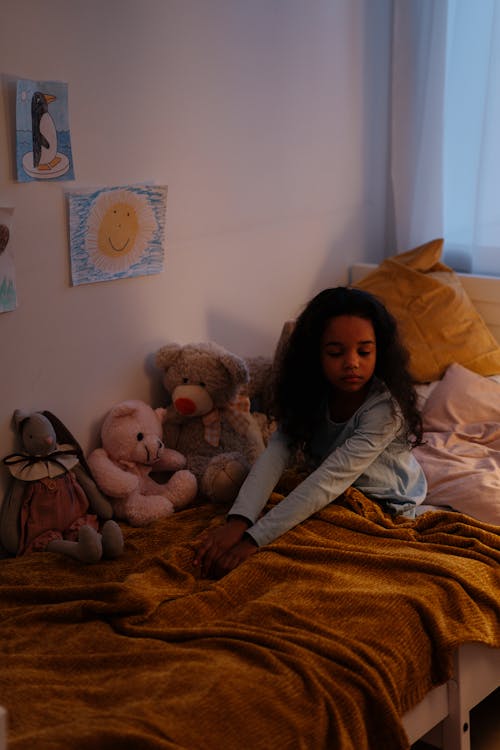 Girl in White Long Sleeve Shirt Sitting on Bed