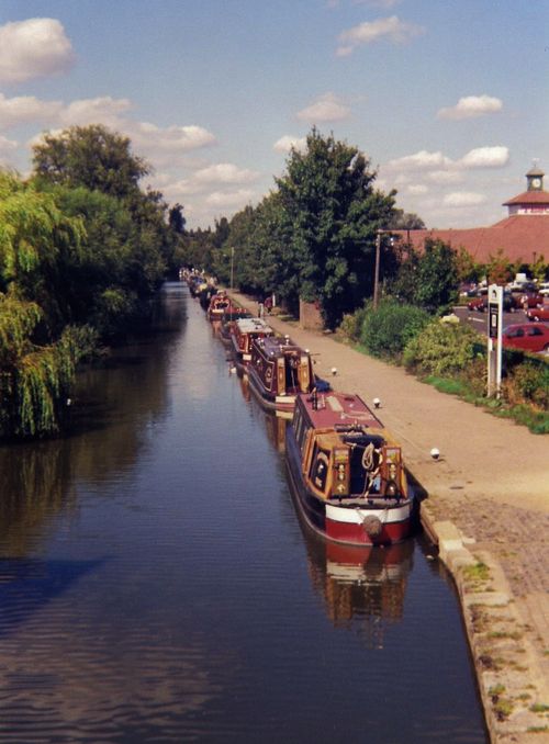 Free Narrowboats docked in a picturesque canal under a clear summer sky. Stock Photo