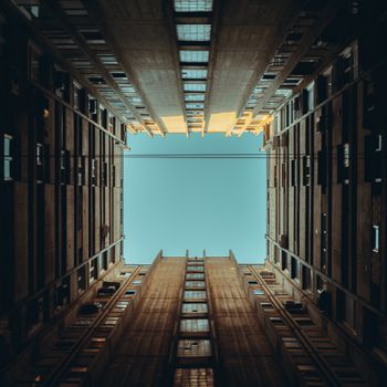 在晴朗的天空下，高耸建筑物的独特向上视图形成了几何框架