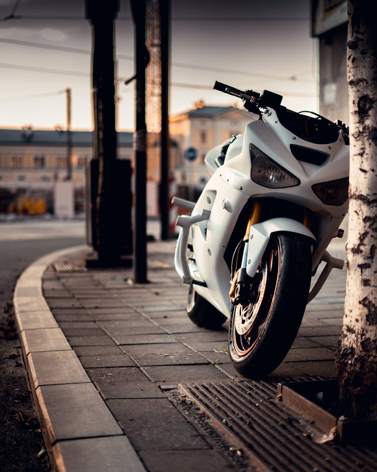 A Parked White Sports Bike On The Sidewalk