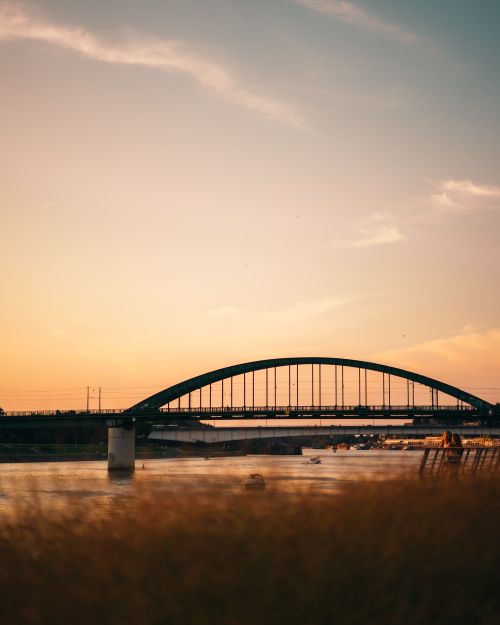 Free Beautiful arch bridge at sunset, with serene lake and vivid sky in the background, perfect for nature and travel themes. Stock Photo