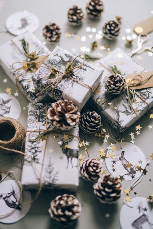 Free Beautifully wrapped Christmas gifts surrounded by pine cones and gold star confetti, creating a festive atmosphere. Stock Photo