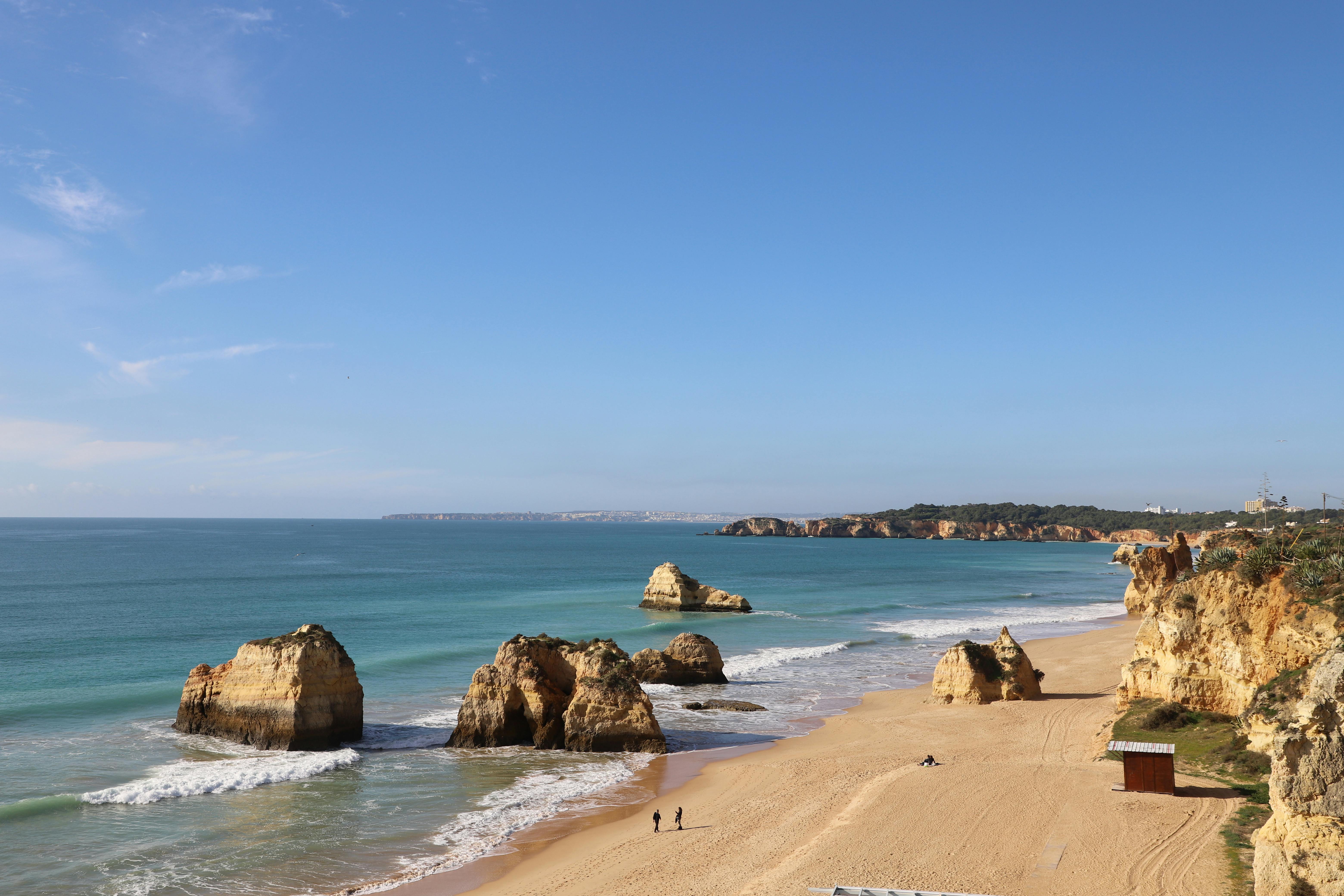 Beautiful view of Praia dos Três Irmãos in Algarve, Portugal featuring rocky cliffs, clear water, and sandy beach.