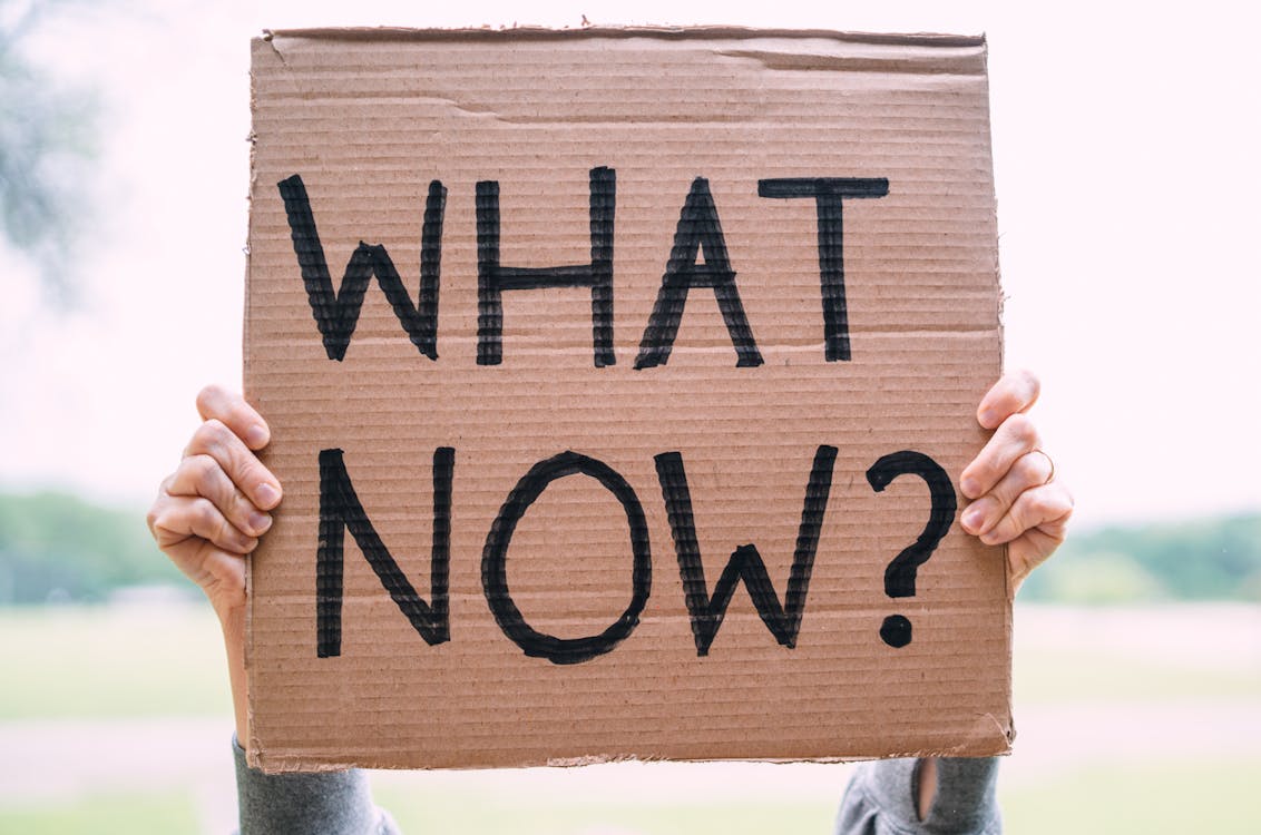 Free Person Holding a Cardboard Banner with What Now Written on It Stock Photo