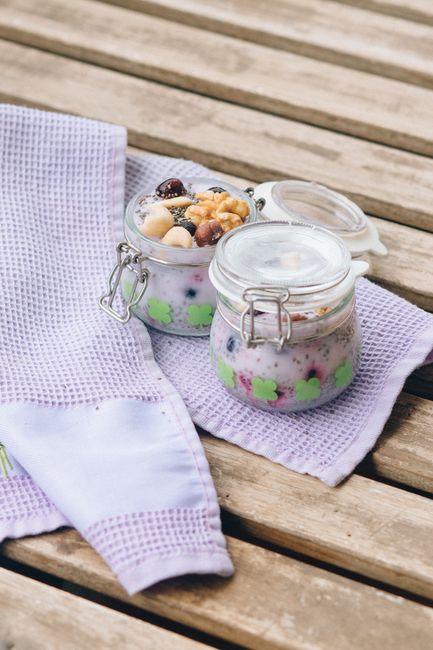 A glass jar layered with thick, set chia pudding topped with sliced strawberries and a drizzle of maple syrup, with a spoon resting beside it.