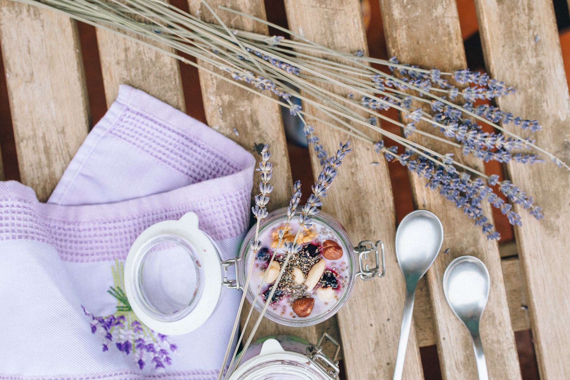 Top view of chia seed pudding with nuts and lavender on rustic wooden table.