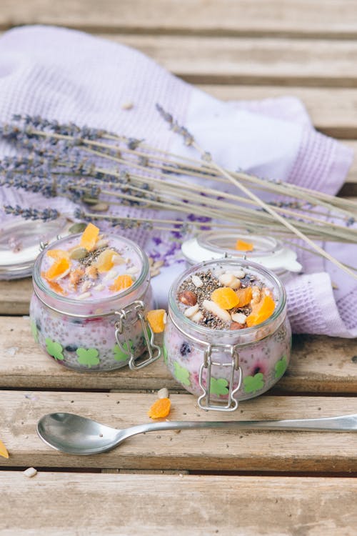 Delicious Desserts in Glass Jars Beside a Pair of Spoons and Textile
