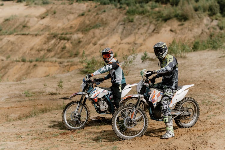 Persons Wearing Helmets And Goggles Sitting On Dirt Bikes