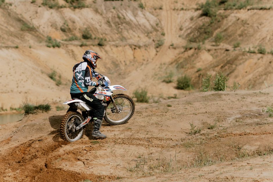 A person on a dirt bike navigating a rugged dirt road in a natural outdoor setting.