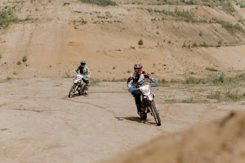 白色和黑色摩托車西裝騎摩托車在棕色沙灘上的男人