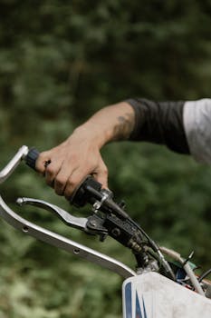 Detailed shot of a motorcyclist gripping the handle of an off-road dirt bike.