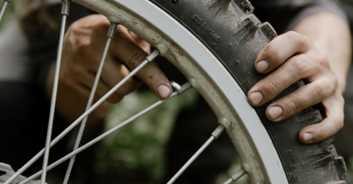 Handen die met bandenlichters een fietsband van de velg halen voor een lekreparatie