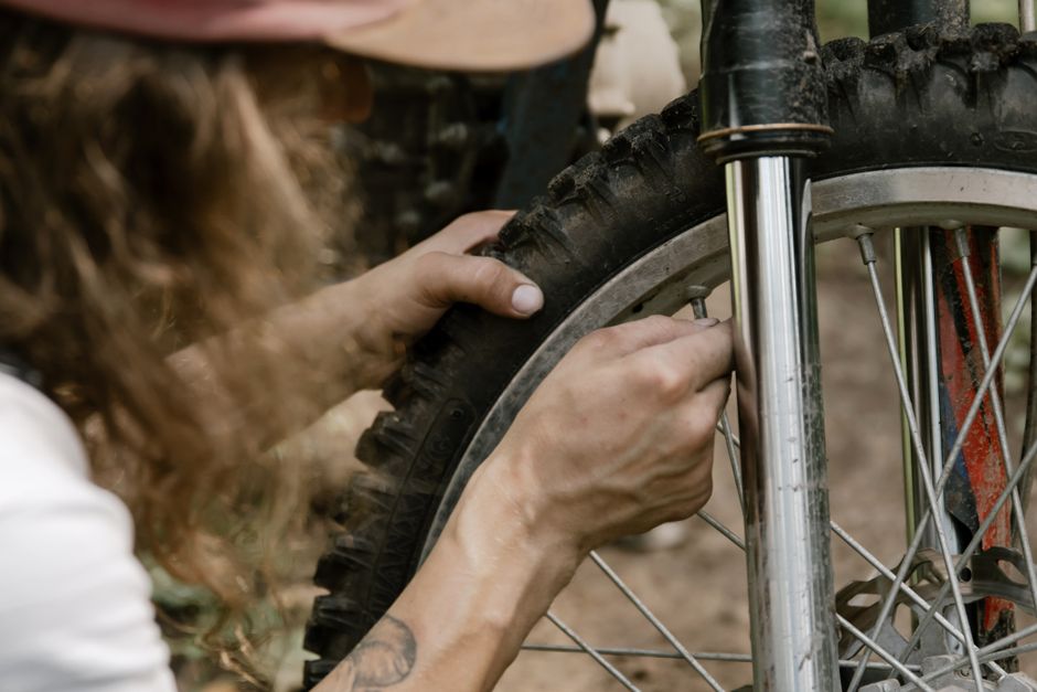 Close-up of mechanic's hands fixing a dirt bike tire in an outdoor setting.