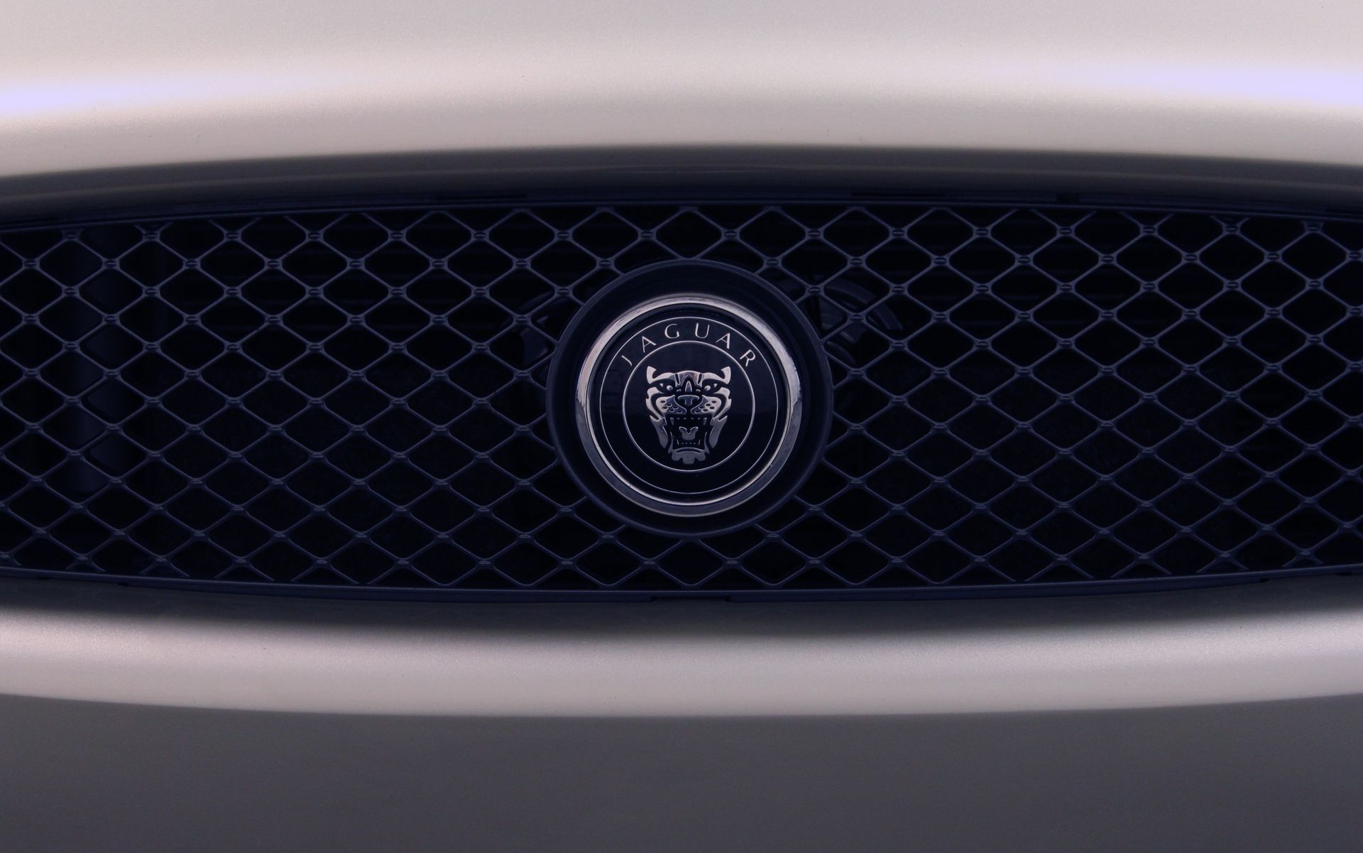 Close-up shot of a Jaguar car mesh grill with emblem - luxury vehicle aesthetics.