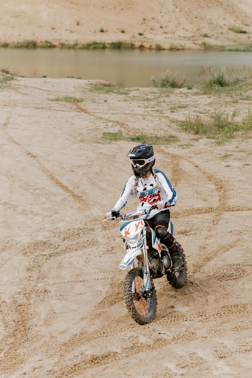 モトクロスダートバイクに乗る青と白のモトクロススーツの男