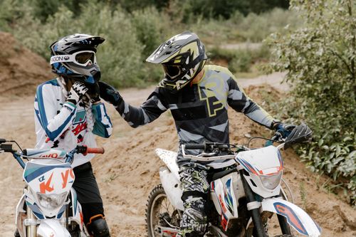 Free Two motocross riders on dirt bikes gearing up on a trail outdoors. Stock Photo