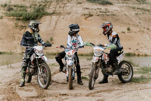 Free Three motocross riders on dirt bikes ready for adventure on an open dirt road. Stock Photo