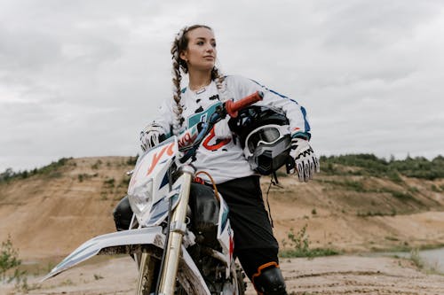 Photo of a Woman in a White Long Sleeve Shirt Riding a Motorcycle