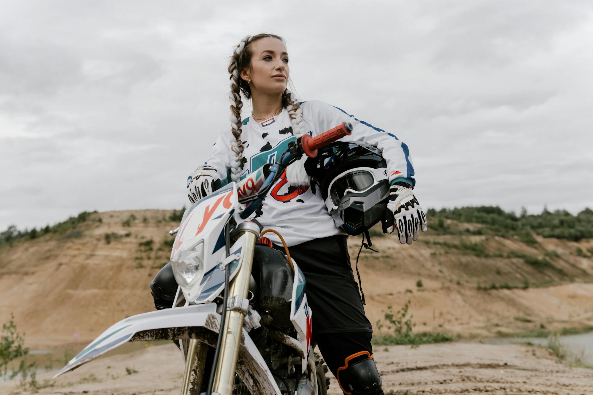 Woman on dirt bike in outdoor landscape, showcasing motocross enthusiasm.