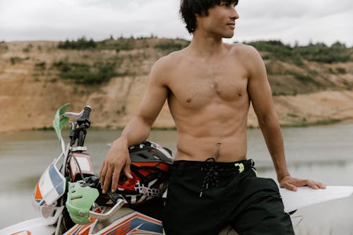 Topless Man En Short Noir Debout à Côté De La Moto Rouge Et Noire