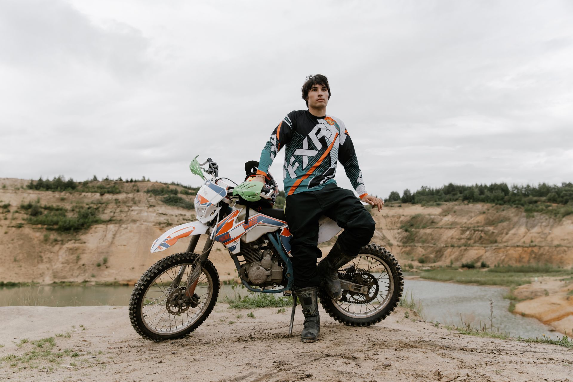 A young man posing confidently on a dirt bike in an open outdoor landscape. Adventure and freedom.