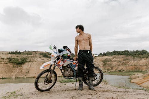 A Topless Man Leaning on a Motorbike