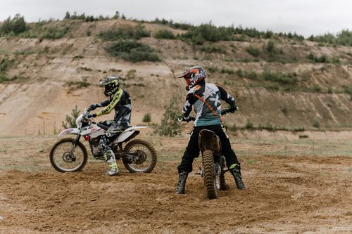Free Two motorcyclists on dirt bikes racing in an outdoor dirt track. Perfect for adventure and sports themes. Stock Photo
