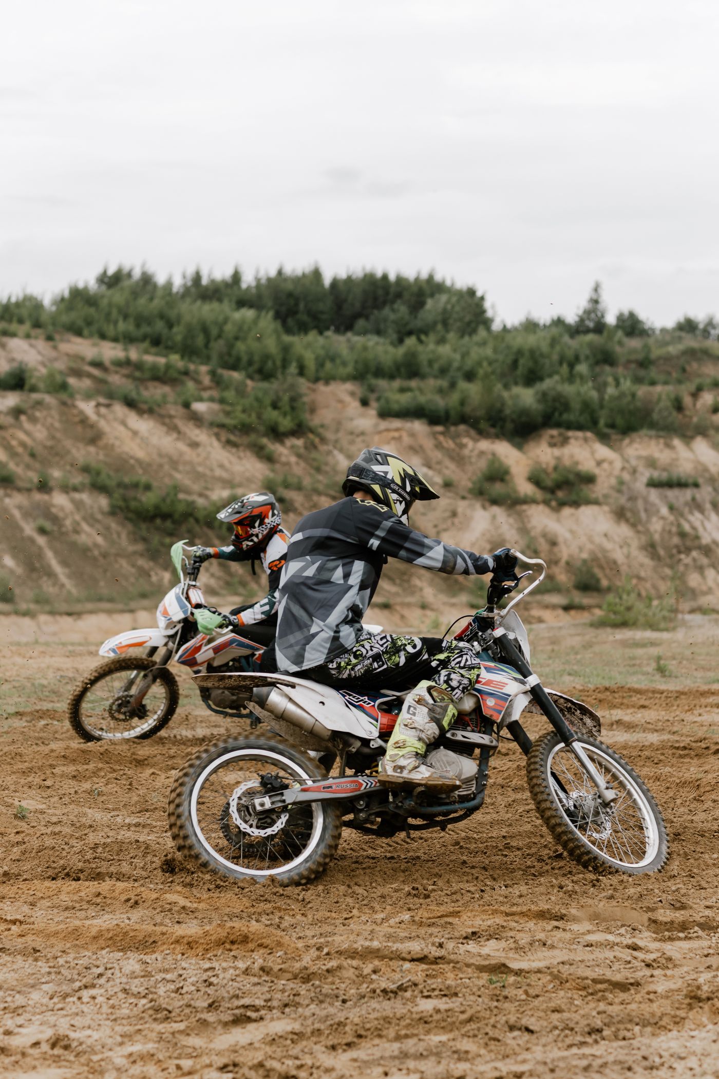 Two riders on dirt bikes on a sandy trail, Cambodia