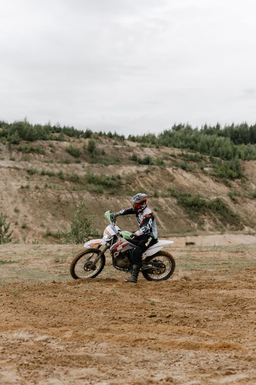 Pilote moto off-road en position debout sur chemin de terre