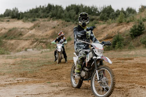 Pria Dengan Setelan Sepeda Motor Hitam Dan Putih Mengendarai Sepeda Motor Trail Motocross