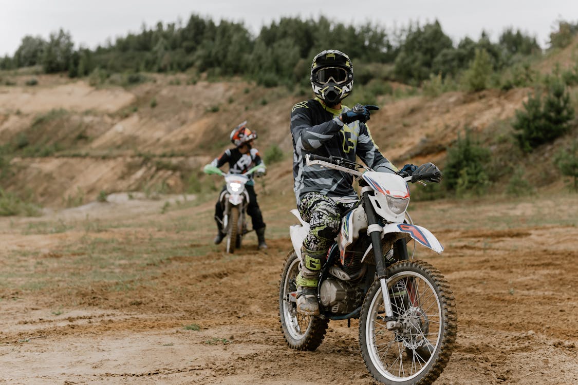 Pria Dengan Setelan Sepeda Motor Hitam Dan Putih Mengendarai Sepeda Motor Trail Motocross