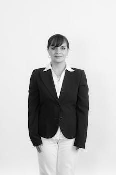 Elegant businesswoman in blazer and white pants on a white background, exuding professionalism.