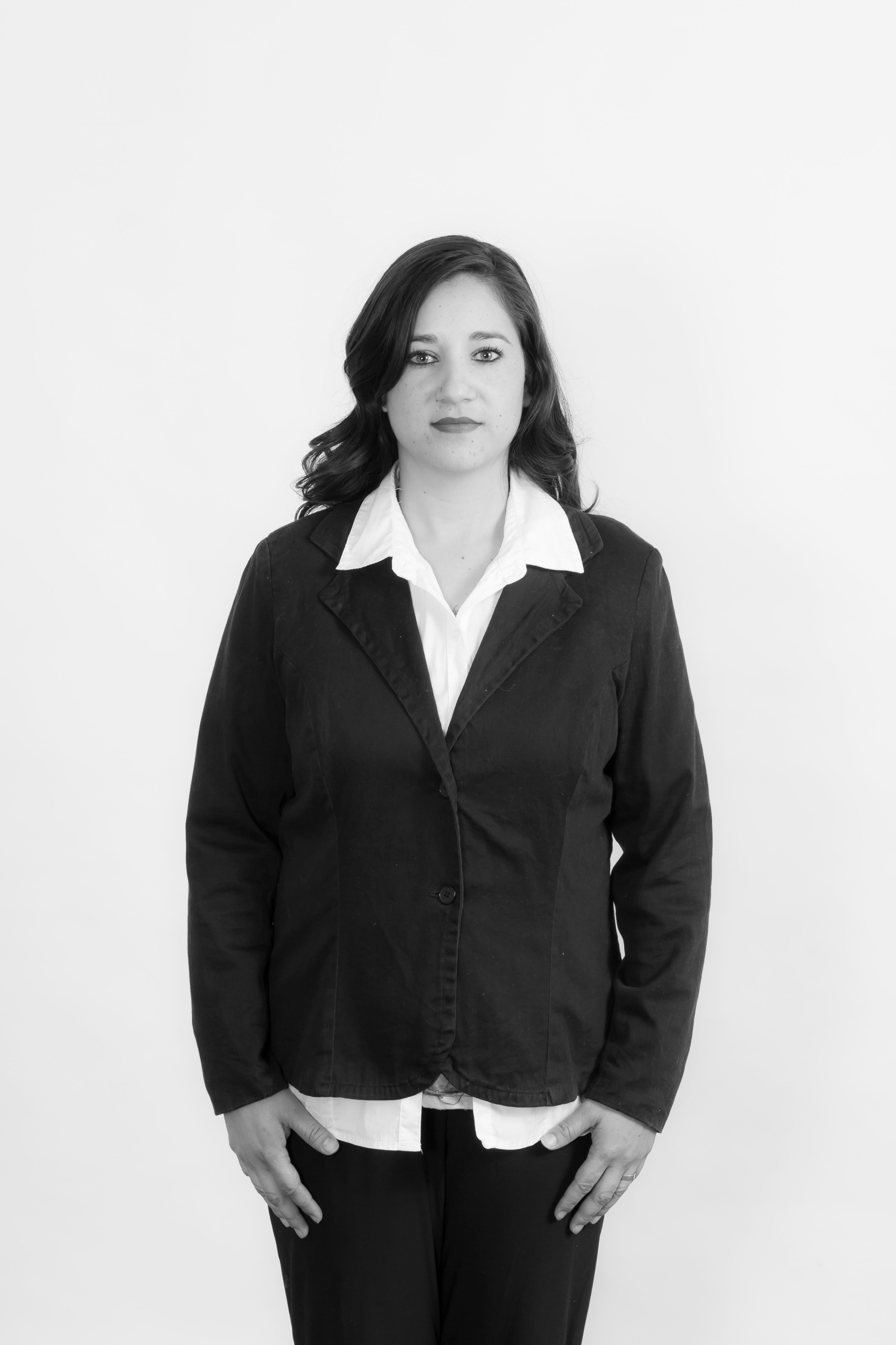 Monochrome photo of a woman wearing a formal suit, looking at the camera.